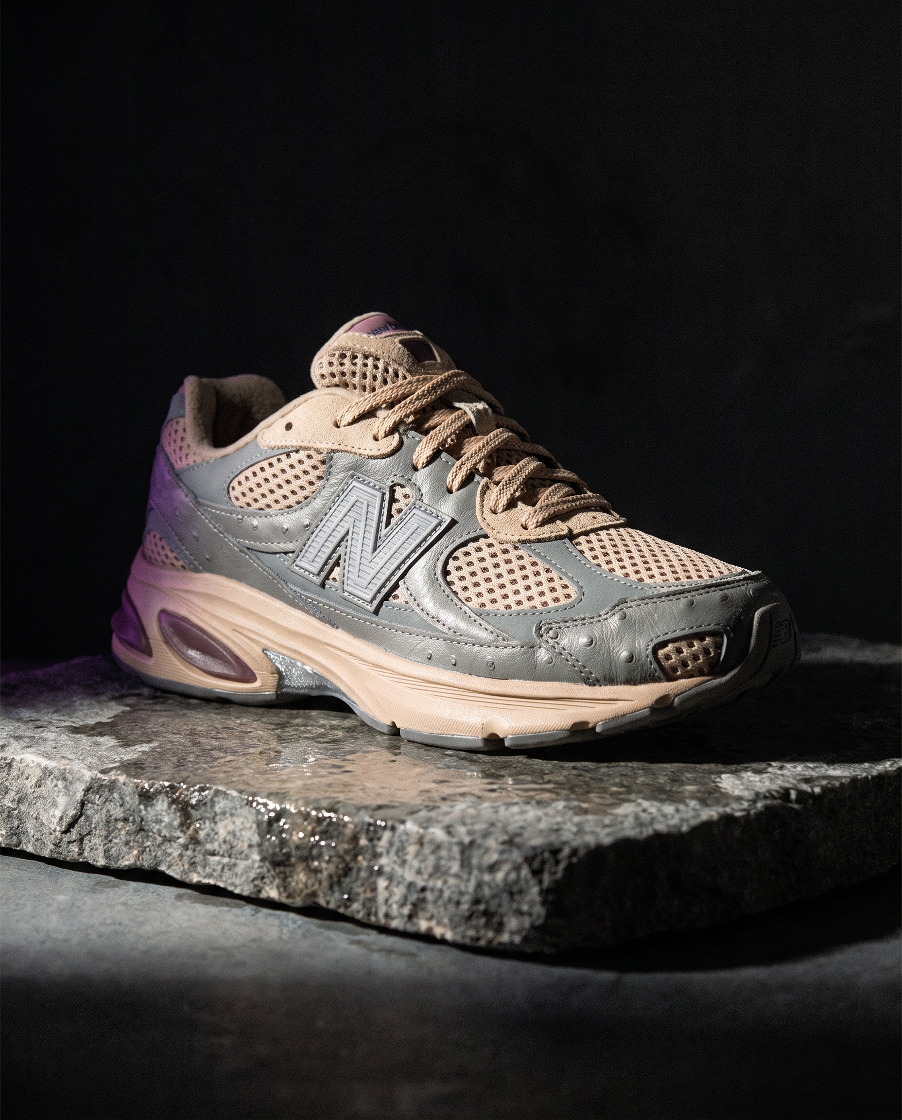 A grey and beige New Balance 2010 sneaker with ostrich-textured leather panels on a slab of wet stone in dark studio light.
